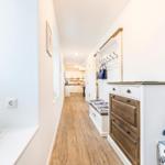 Flur mit Holzboden, Garderobe und Schuhschrank. Küchenbereich im Hintergrund.