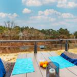 Terrasse mit Tisch, Stühlen und Blick auf Wald und Himmel.