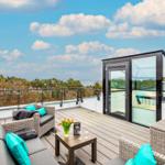 Terrasse mit Sitzgruppe und Blick auf Wald und Meer.