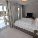 Schlafzimmer mit Doppelbett, Fernseher und Balkon mit Blick auf Wald.