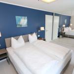 Schlafzimmer mit Doppelbett, blauer Wand und Spiegelschrank.