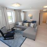 Wohnzimmer mit Sofa, Sessel und Küchenbereich