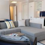 Wohnbereich mit Sofa, Couchtisch und Küchenzeile mit weißen Schränken.