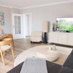 Wohn- und Essbereich mit TV, Sofa, Esstisch und Kunstwerk an der Wand.