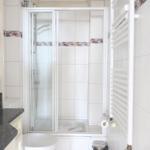 Badezimmer mit Dusche, Waschbecken und Heizung.