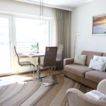Living and dining area with sofa, table and chairs. Large windows and wall picture.