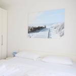 Bedroom with white bed, wall art, and wardrobe