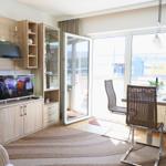 Living room with TV, dining area, and balcony door. Furniture and fittings are modern.