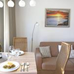 Dining table for two, beside sofa with cushions and wall picture.