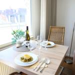 Dining table with two plates, wine bottle, and chairs by window with view.