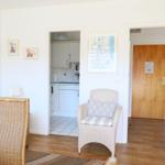 Living area with seating, kitchen area, and entrance door.