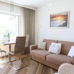 Living room with sofa, table and chairs, wall art and large window.