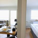 Wohn- und Schlafzimmer mit Tisch, Bett und Fenster. Einrichtung modern und funktional.