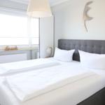 Schlafzimmer mit Doppelbett, Fenster und Wanddekoration.