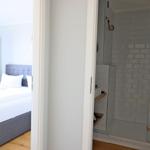 Schlafzimmer mit Bett und Badezimmer mit Dusche und Fliesen
