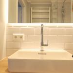 Waschbecken mit Spiegel und modernem Wasserhahn