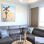 Grauer Sofa mit Kissen und Wandbild an der Wand.