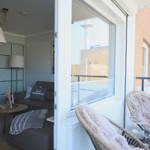Wohnbereich mit Balkon, Sitzmöbel und Blick auf Stadtlandschaft.