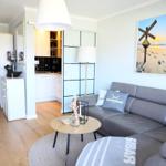 Wohnzimmer mit Sofa, Couchtisch und Küchenbereich im Hintergrund.