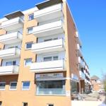 Multi-family building with balconies and glass railings under blue sky.