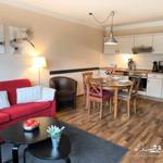Wohnzimmer mit rotem Sofa, Esstisch und Küche im offenen Raum.