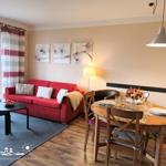 Wohn- und Essbereich mit rotem Sofa, Holztisch und Fensterblick.