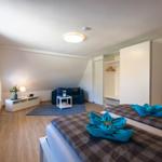 Room with two beds, wardrobe, and seating. Blue towels as decoration.
