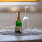 On the table is a green bottle and two champagne glasses.