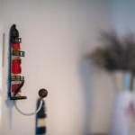 Wall-mounted lighthouse-shaped hook. A vase with flowers is in the background.