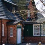 Haus Nordstrand with red brick, green roof, white door, and white windows.