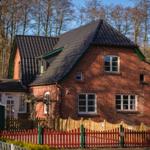 Red brick building with green accents and wooden fence. Surrounded by trees.