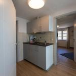 Kitchen with worktop, sink, and cabinets. Background: living room with window.