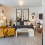 Living room with gray sofa, yellow armchair, and white furniture.