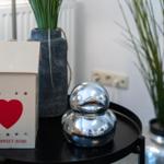 On a table, a lantern with a heart and a shiny duck sit beside plants.