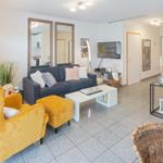 Living room with sofa, yellow chairs, and kitchen area.