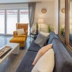 Living room with gray sofa, yellow armchair, and mirrored wall.