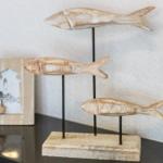 Three wooden fish on stands, next to a lighthouse picture.