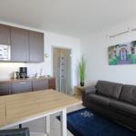 Living area with sofa, dining table, and kitchenette with microwave.