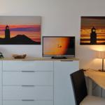 Desk area with TV, two wall pictures, and a lamp.