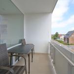 Balcony with table and chairs. View of street and houses.