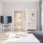 Living room with TV, bookcase, and seating. Passage to dining and bedroom.