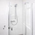 Shower cabin with glass door and shower head on the wall