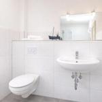 Bathroom with toilet, sink, and mirror. Decoration: model sailboat.