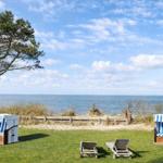 Two beach chairs and two loungers on a green lawn with a view of the sea.