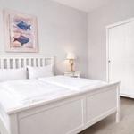 Bedroom with white bed, wardrobe, and wall art with fish.