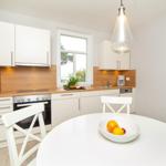 Kitchen with dining area, white cabinets, wooden backsplash, and window view.