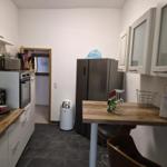 Küche mit Kühl-Gefrierkombination, Esstisch und Arbeitsplatte aus Holz.