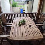 Holztisch mit vier Stühlen auf Terrasse. Tisch mit Pflanze und Dekoration.