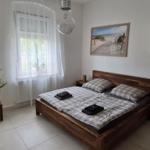 Schlafzimmer mit Holzbett, Fenster mit Vorhängen und Wandbildern.