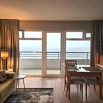 Wohn- und Essbereich mit Blick auf das Meer durch Glastüren.
